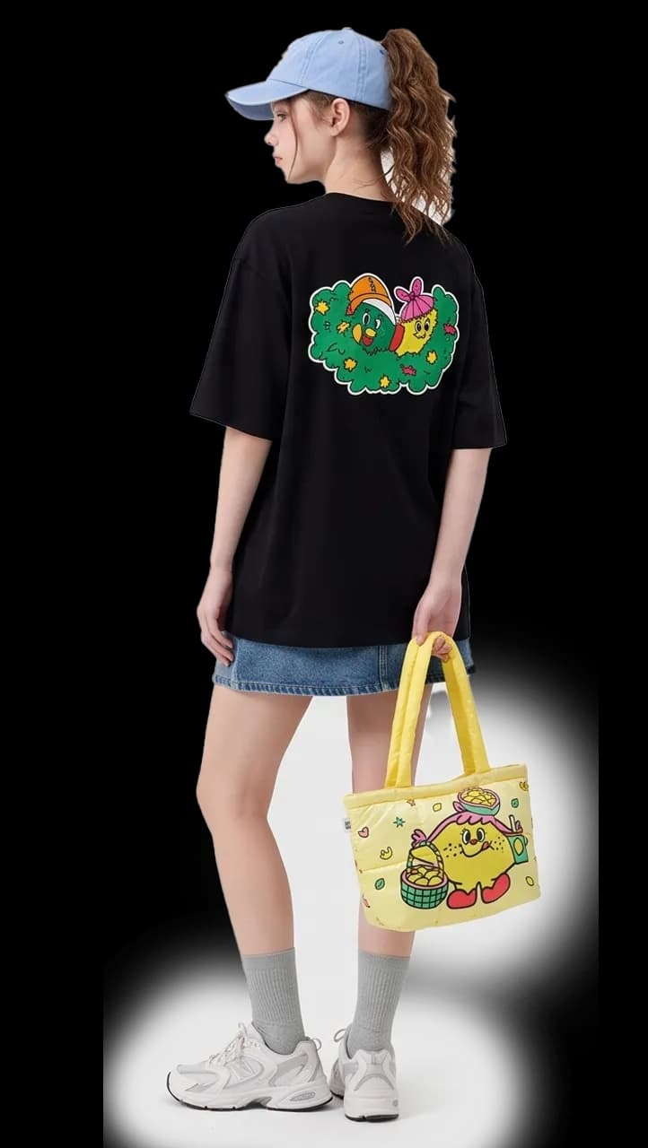 Model in a black Giggle Crumble graphic tee carrying a yellow tote